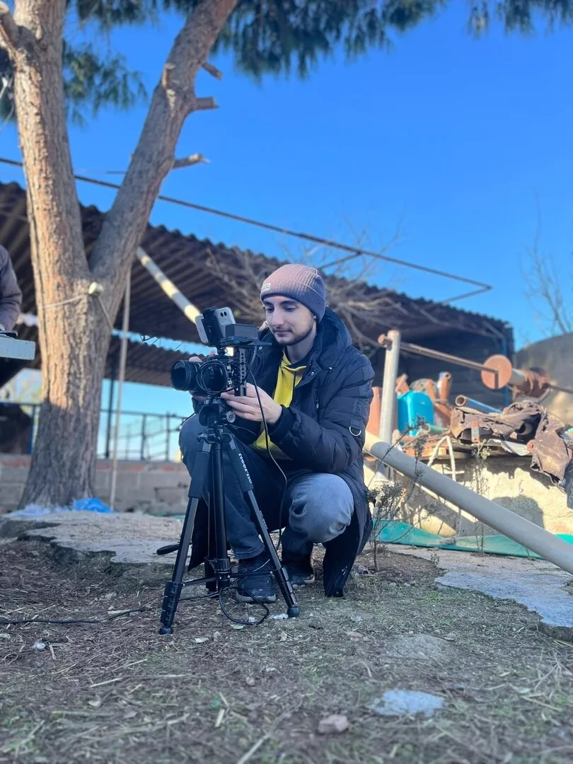 Filming from a tripod beside a ruined building